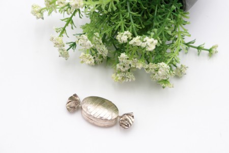 Caixa de comprimidos em prata e forma de rebuçado com bandas alternadas lisas e 